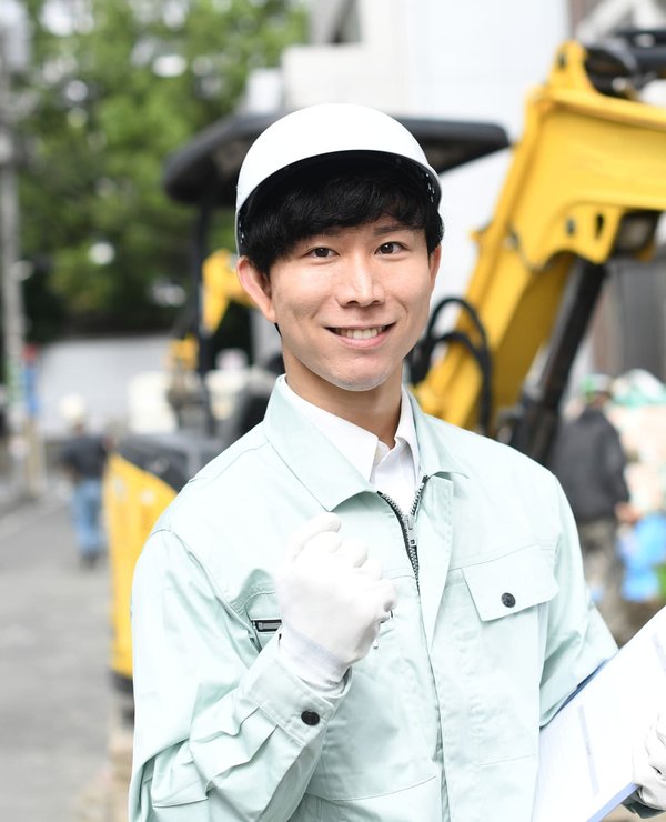 油圧ショベルの前でガッツポーズをする建設機械整備士