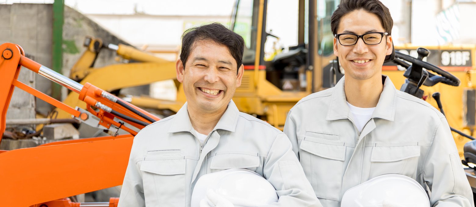ホイールローダーの前に並ぶ建設機械整備士