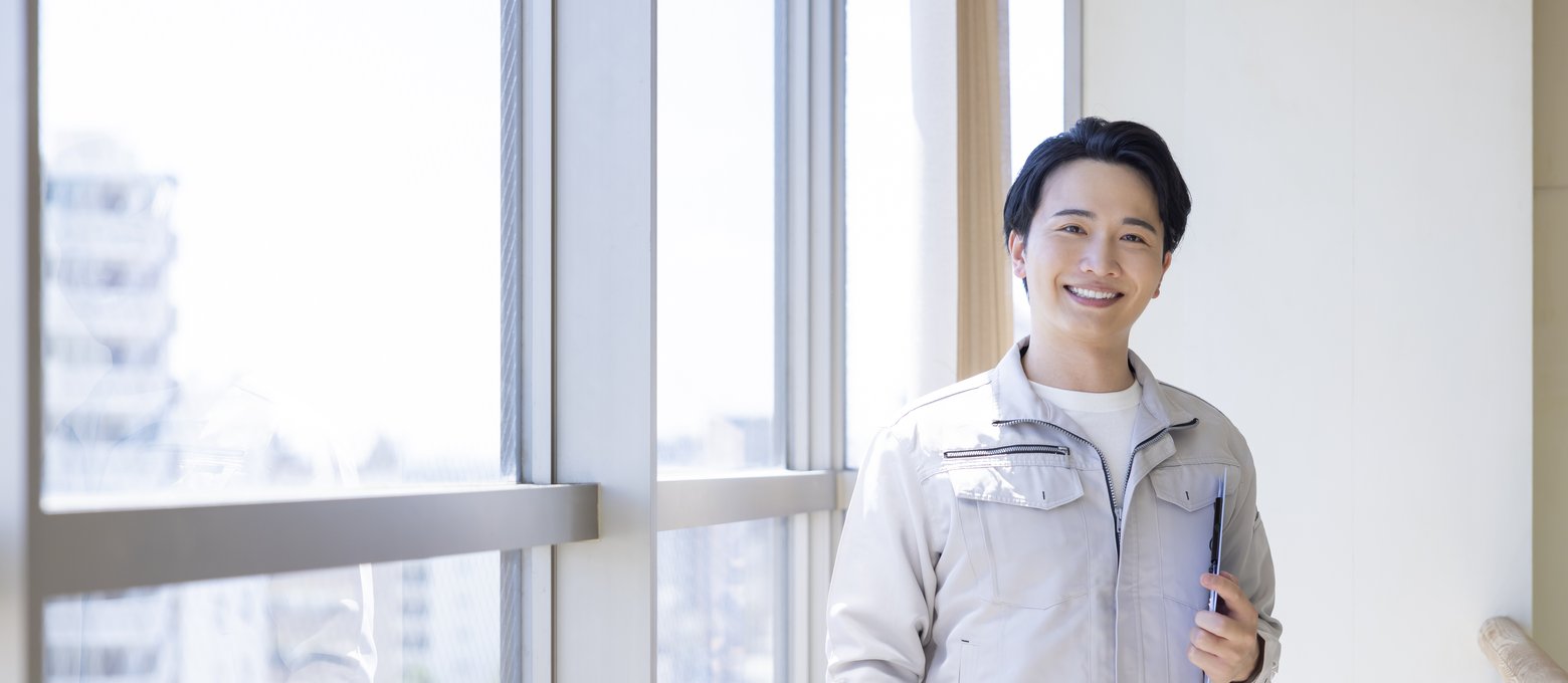 窓際に立つ作業着姿のフィールドエンジニア