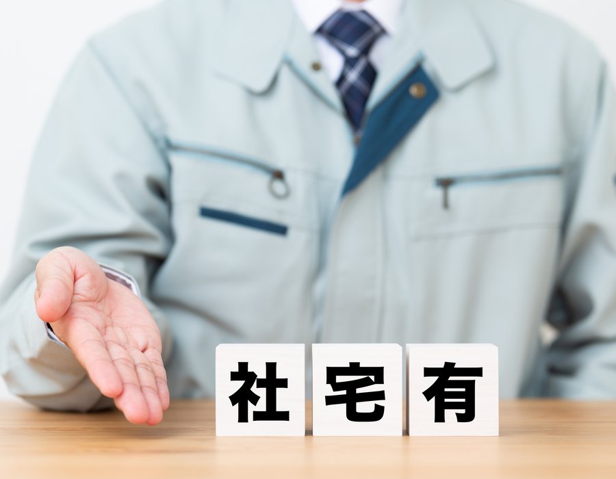 「社宅有」と書かれた積み木を示す作業着姿の男性