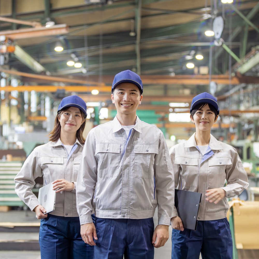 工場に並ぶ作業着姿のメカニック3人